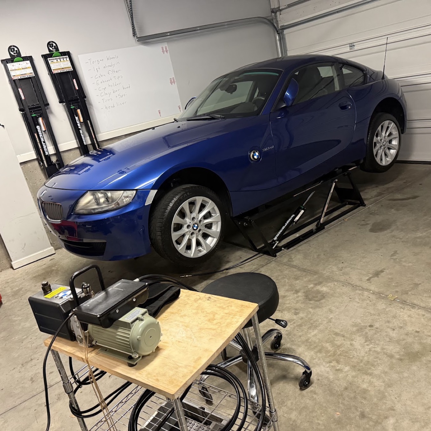 The 2008 Z4 Coupe up on the QuickJack with the to-do whiteboard behind it