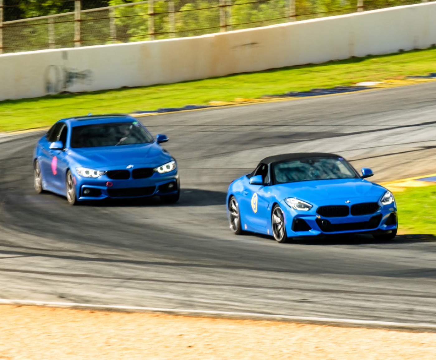 Two blue BMWs mid-corner at Road Atlanta: the #9 Z4 sDrive30i chasing the 428i Gran Coupe